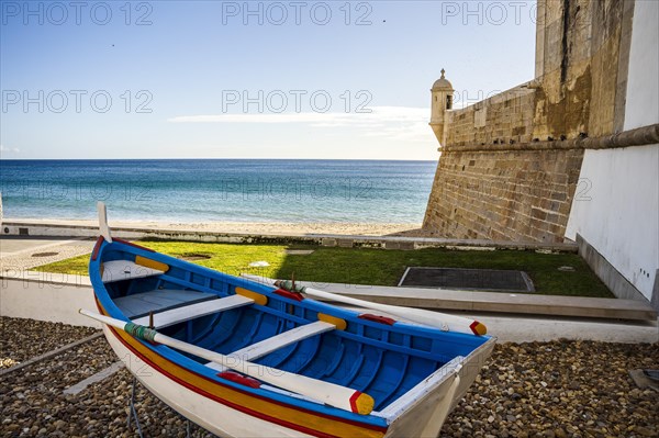 The wooden traditional boat and Saint James Fortress on the beach of Sesimbra