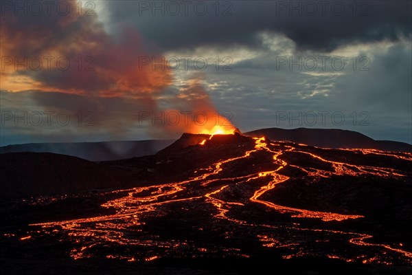 Lava spurting out of crater and reddish illuminated smoke cloud