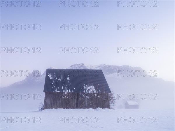 Hut in front of mountain peak of the Reichenstein group and landscape in the fog