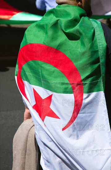 A man wears the Algerian flag as a cape at a protest