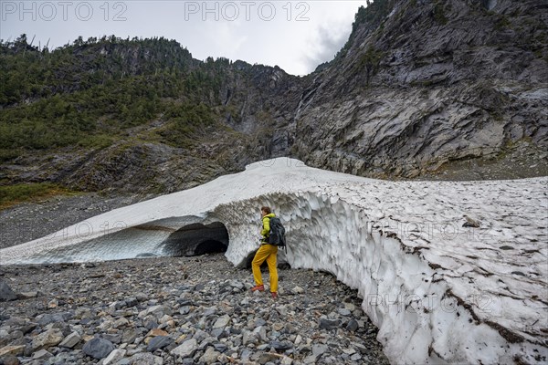 Hikers at the entrance of an ice cave of a glacier