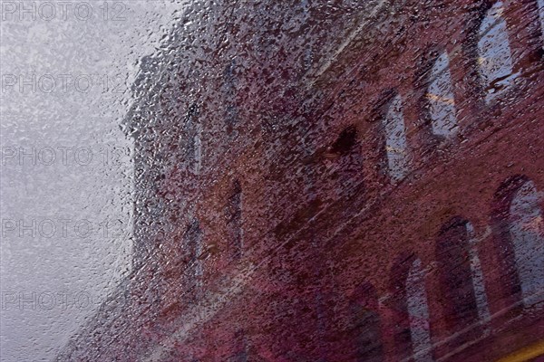 Red brick house reflected in rain puddle
