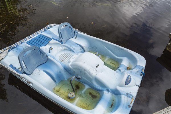 Blue Pelican pedal boat filled with rainwater in summer