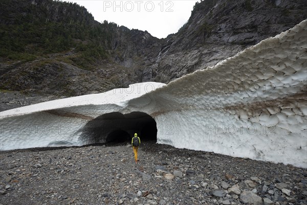 Hikers at the entrance of an ice cave of a glacier