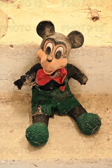 Demolished rag doll of a Mickey Mouse leaning against the wall