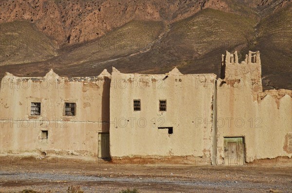 Clay fortress with tower in front of mountain wall