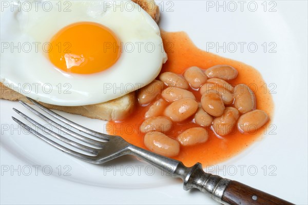 White beans with tomato sauce and fried egg on toast