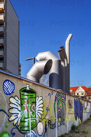 High-rise building with concrete balconies and ventilation pipes and wall with graffiti