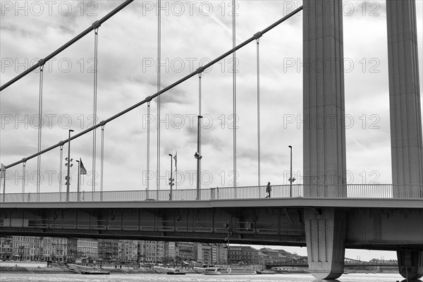 Pedestrian walking over steel suspension bridge