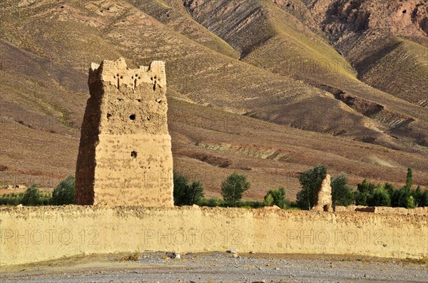 Clay fortress with tower in front of bare mountains