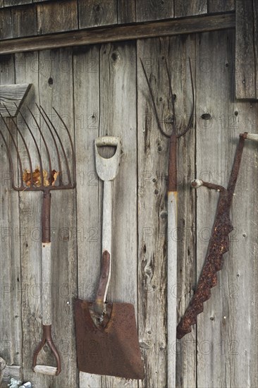 Antique hand tools displayed on exterior wall of old rustic wood plank cabin