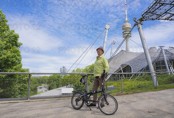 Man with bicycle at the Olympic Tower with Olympic tent roof