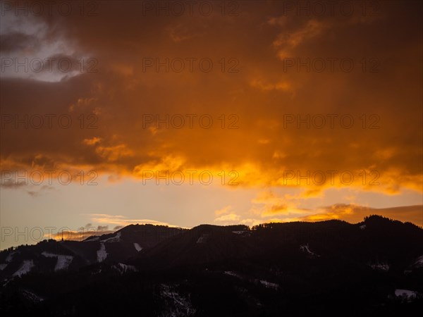 Clouds above the summit of the Mugel in the morning red at sunrise