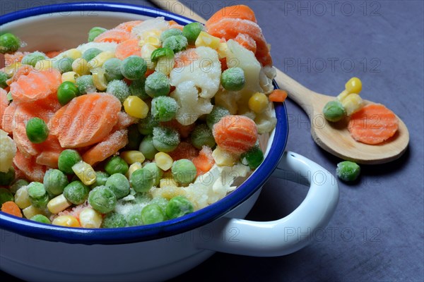 Frozen vegetables in bowl with cooking spoon