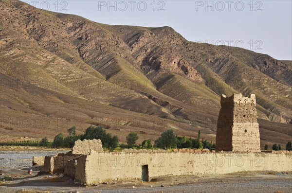 Clay fortress with tower in front of bare mountains