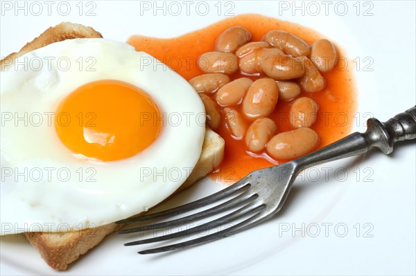 White beans with tomato sauce and fried egg on toast