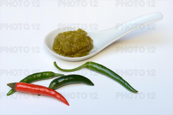 Green Thai curry paste in ceramic spoon and chillies