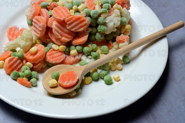 Frozen vegetables on plate with cooking spoon