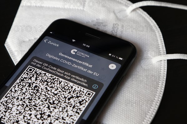 FFP2 mask and iPhone with Corona warning app with QR code for certificate of recovery