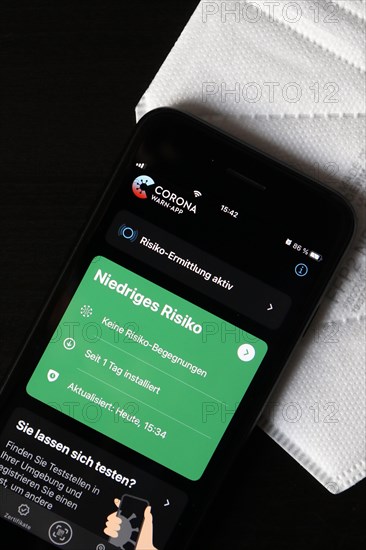 FFP2 mask and iPhone with low-risk Corona warning app