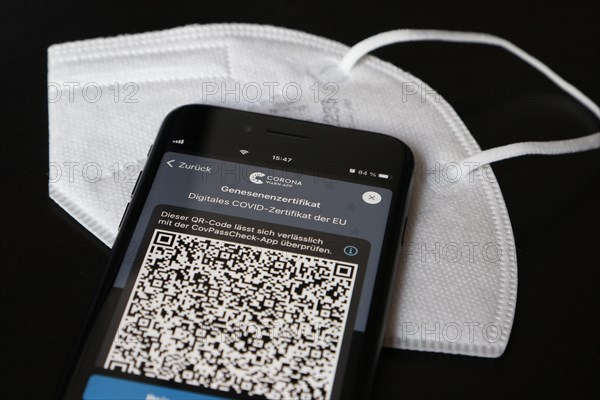 FFP2 mask and iPhone with Corona warning app with QR code for certificate of recovery