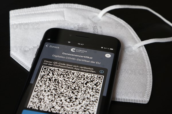 FFP2 mask and iPhone with Corona warning app with QR code for certificate of recovery