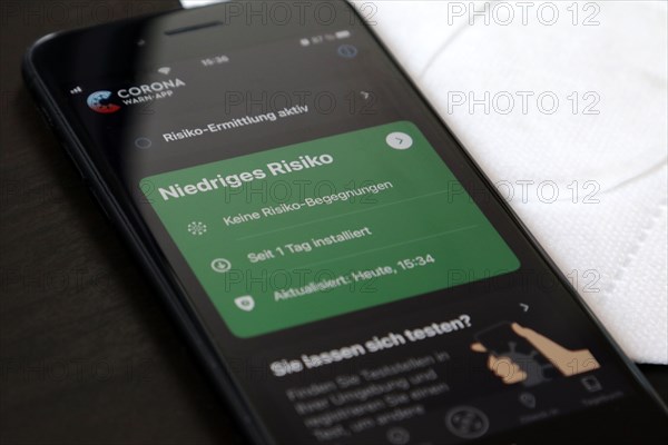 FFP2 mask and iPhone with low-risk Corona warning app