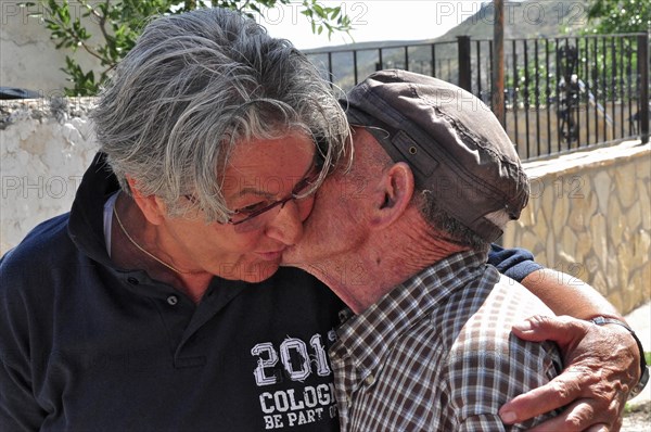 Older woman hugs old man who kisses her cheek