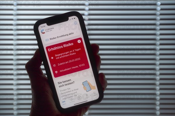 Hand holding smartphone with Corona warning APP