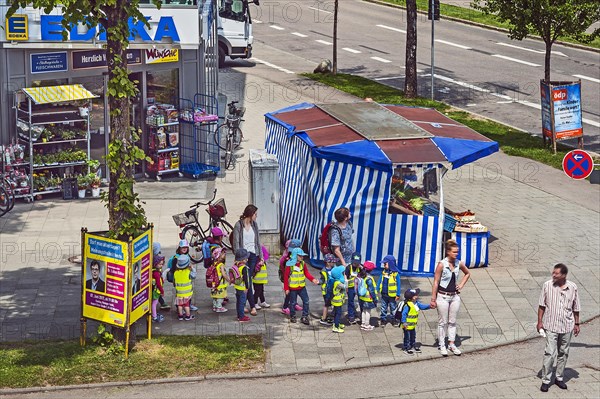 Fruit stand and kindergarten children with high visibility waistcoats