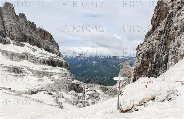 Snow-covered pass Bocca del Tuckett with hiking sign