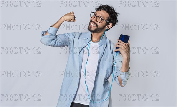 Happy man with headphones holding a cell phone and celebrates