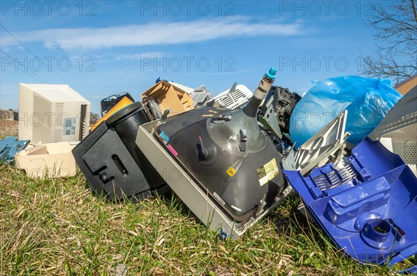 Polluting plastic waste and computer scrap illegally disposed of in a meadow