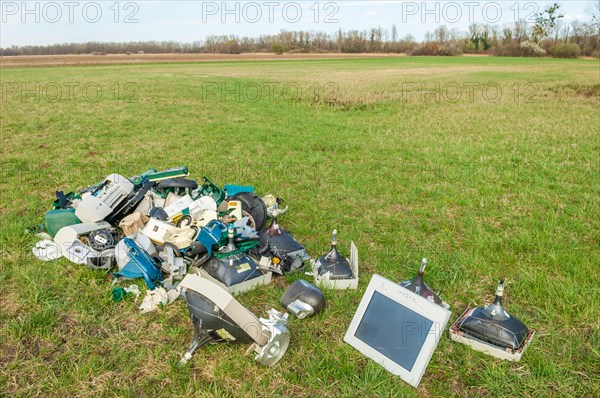 Polluting plastic waste and computer scrap illegally disposed of in a meadow
