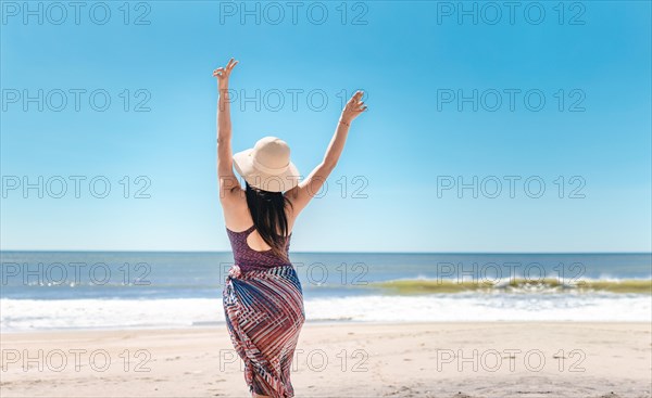 Woman with hat from back on the beach
