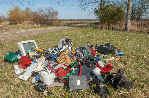 Polluting plastic waste and computer scrap illegally disposed of in a meadow