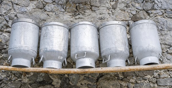 Milk cans lined up on a wooden bench