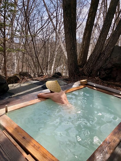 Young man with Japanese hat bathes in an onsen