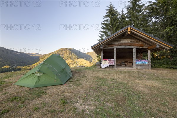Green tent near hut on dry summer meadow