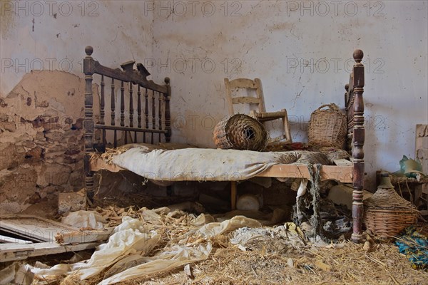 Wooden Marriage Bed with Chair and Wine Bottles in Baskets in Abandoned House