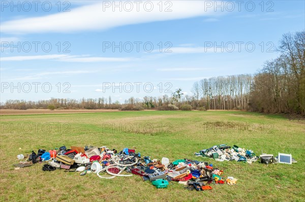 Polluting plastic waste and computer scrap illegally disposed of in a meadow