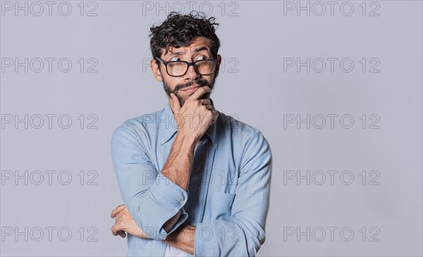 Young man wondering with his hand on his chin on an isolated background