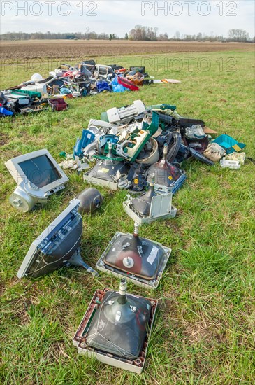 Polluting plastic waste and computer scrap illegally disposed of in a meadow