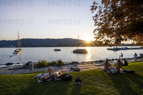 People sunbathing on the shore of Lake Zurich