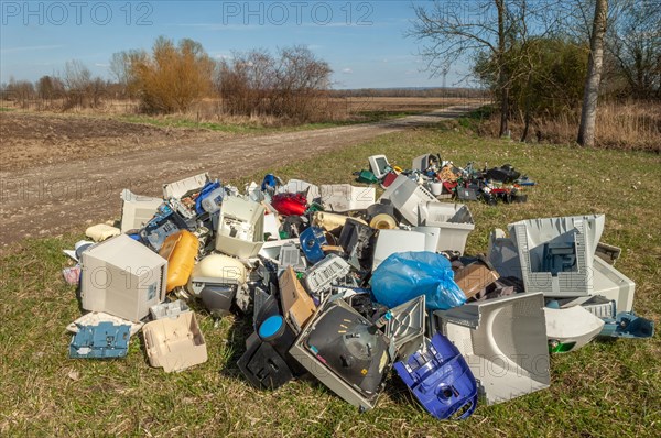 Polluting plastic waste and computer scrap illegally disposed of in a meadow