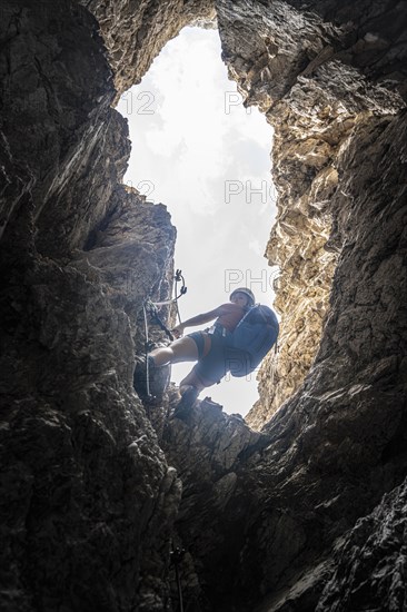 Young woman climbing a steep rock face