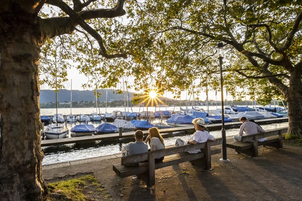 People sitting on benches on the lakeside promenade at Lake Zurich