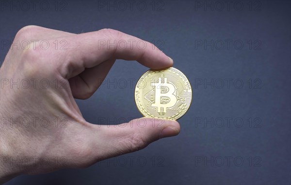 Man hand holding a Bitcoin BTC crypto currency gold coin