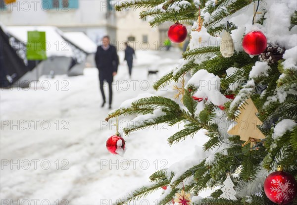 Beautiful Christmas tree detail and blurred people walking through the snow in winter day
