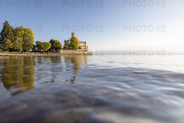 Autumn trees on the shore in the sunshine with Montfort Castle